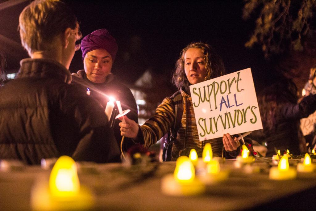 Grinnell College students hold signs and candles in support of survivors at last Thursdays vigil. Paul Chan.