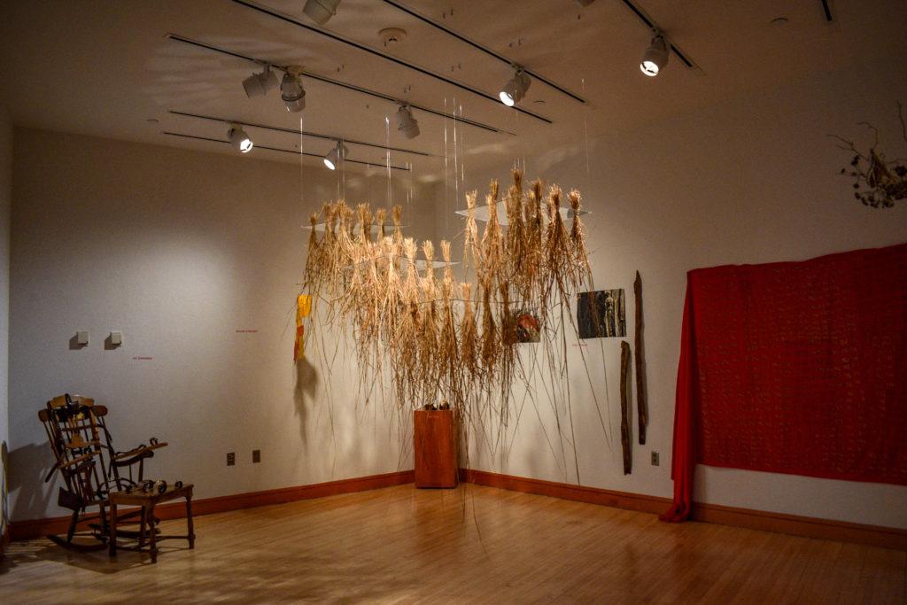 Prairie grass hangs in the center of the gallery, inviting visitors to navigate the space. Photo by Reina Shahi. 