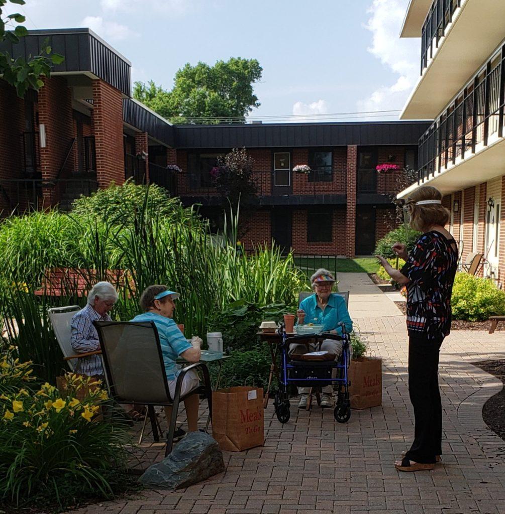 A Mayflower staff-member in a face shield speaks with residents of the Mayflower. Photo contributed by The Mayflower.