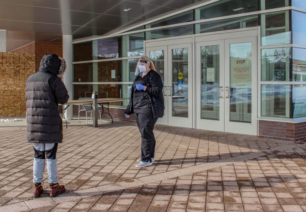 A SHAW staffer and a student outside the Charles Benson Bear recreational center, where students and staff at Grinnell go for weekly testing. Photo by Kaya Matsuura.