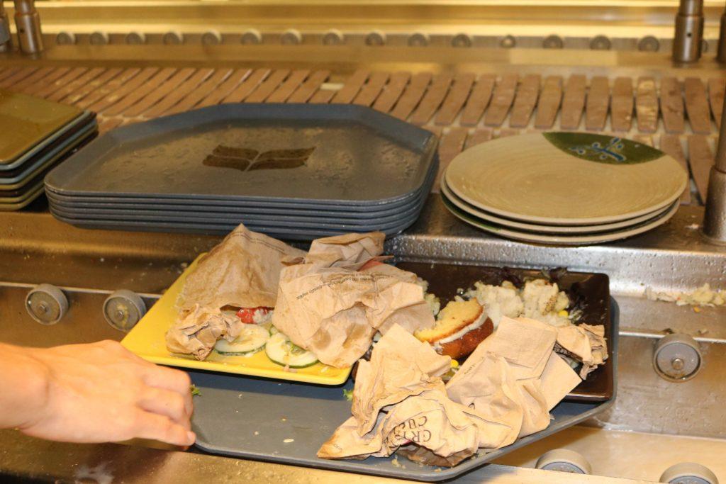 Tray with discarded leftovers and napkins being put on the dish line.