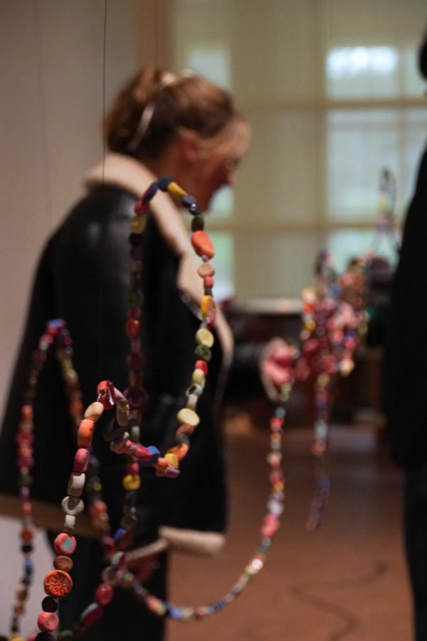 A gallery visitor plays with one of the many colored beads strung together on a long wire.