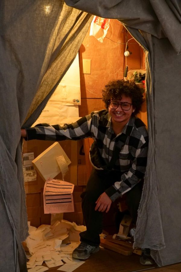 Mordecai posed smiling in their structure constructed out of wood and found Grinnell College objects.