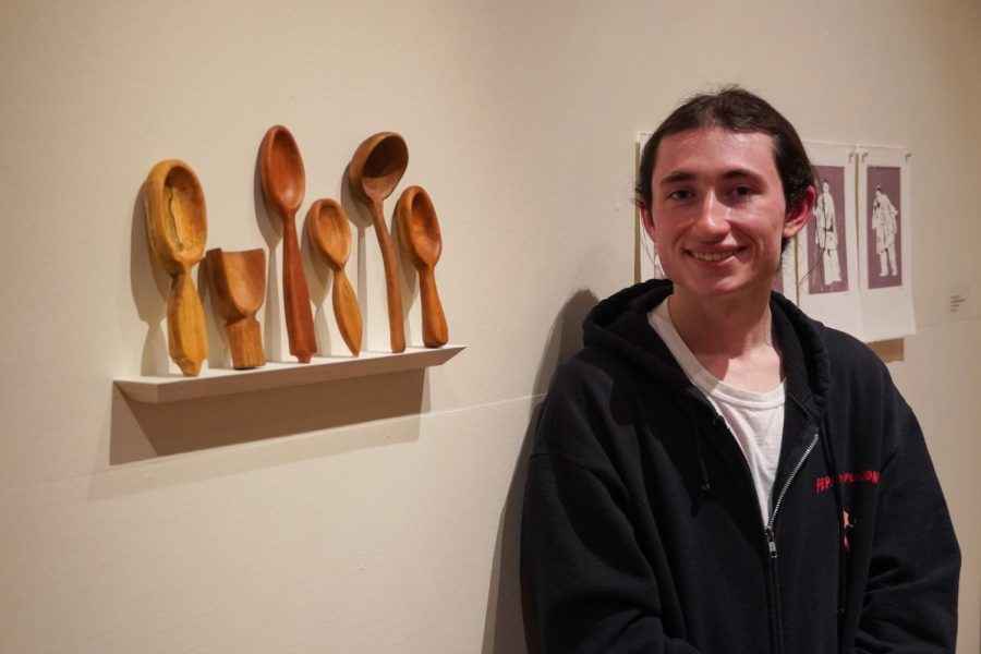 Kelly Banfield posing next to his spoons displayed on a shelf.