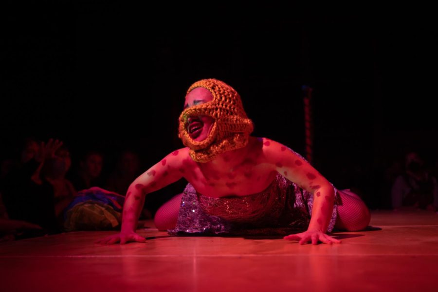 Sushi Salmon crawls along the stage on hands and knees with a yellow crochet head piece over the face and red splotches along both arms.