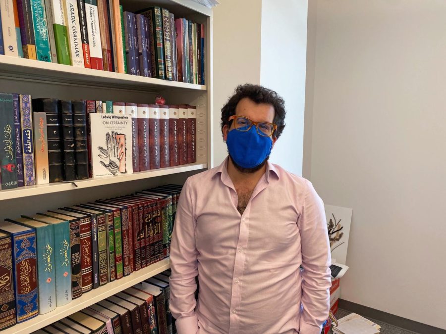 Elias Saba standing in front of the bookshelf in his office
