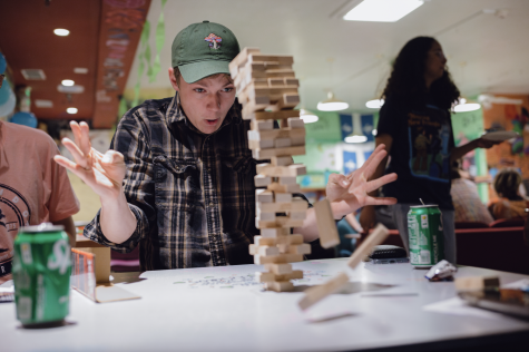 A student reacts in surprise as a jenga tower crumbles before them.