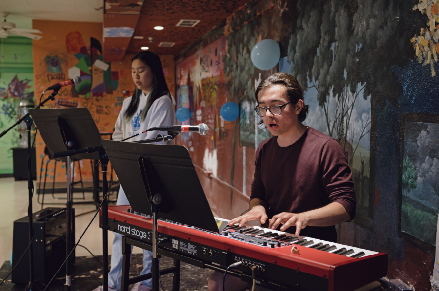 Daniel Stewart plays the keyboard next to Caitlin Ong singing.