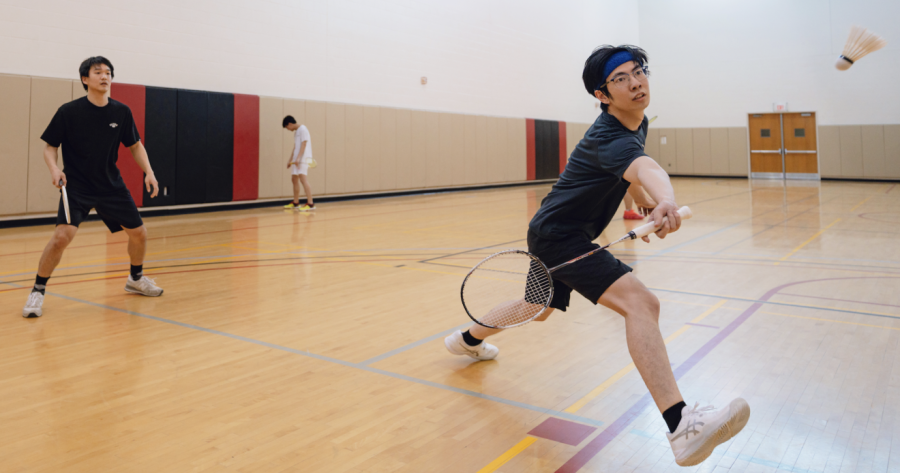 Kevin Qiu lunges forward with his racket while Andrew Park waits behind him poised to receive the next volley.