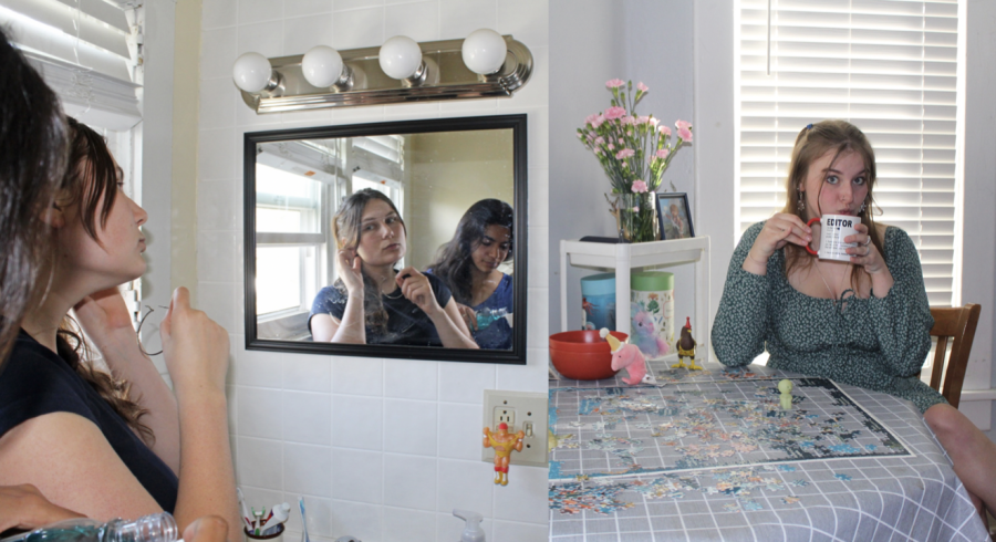 Nadia Langley and Athena Frasca look into the bathroom mirror. Allison Moore sips from a mug while seated at her dining room table.