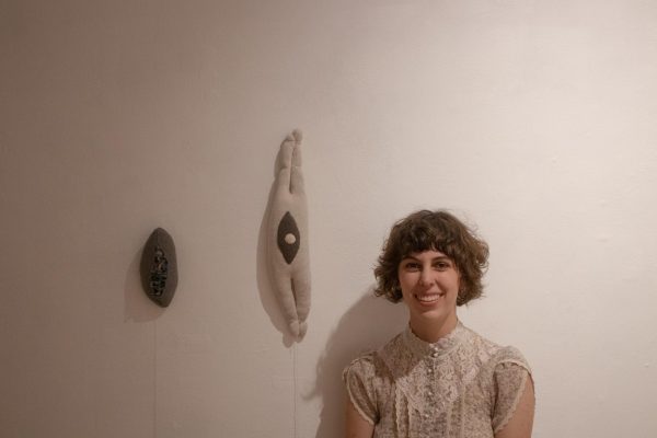 Artist Liv Hage `25 poses with work from her exhibit Flesh/Blood at the Edith Renfrow Smith `37 Student Art Gallery.