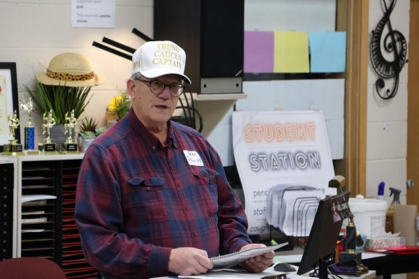 Ken Philips, wearing a Trump Caucus Captain cap, delivers a speech on why voters should cast their ballots for Donald Trump at the Grinnell High School Precinct.