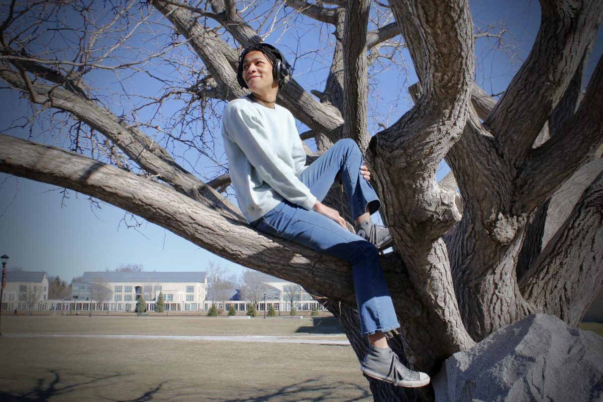 Marcy Cassidy-Mapp `24 sits in a tree on Mac Field while listening to music.
