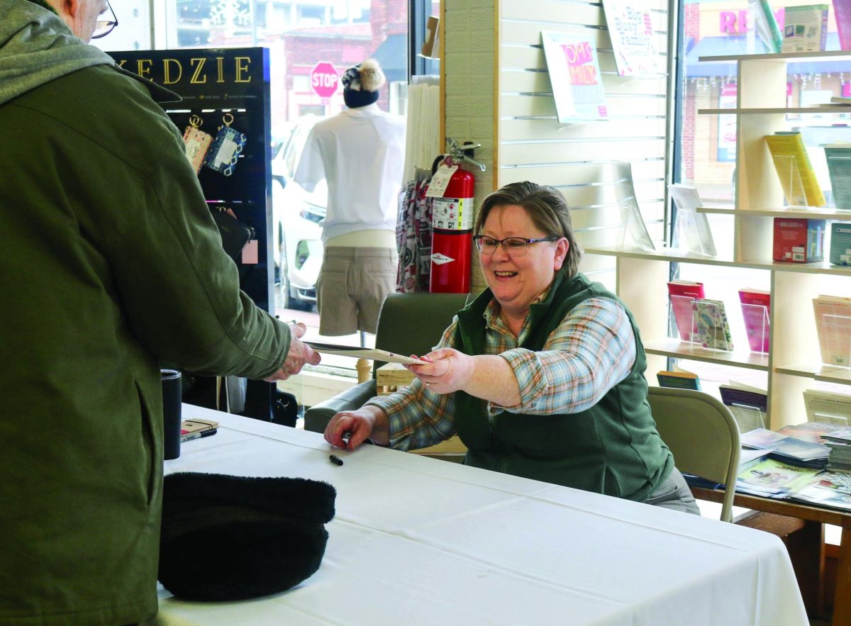Writer Monique McLay Shore `90 signs local community member Joe Noers copy of No One Is Better Than You.