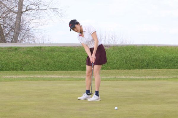 Amy Nguyen `26 putts the ball towards a hole at a team practice at the Grinnell College Golf Course.