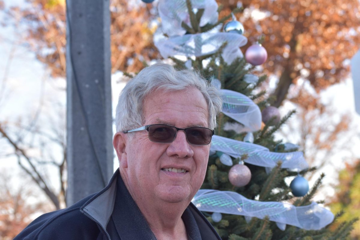 Jim White smiles warmly in front of a Christmas tree in downtown Grinnell.
