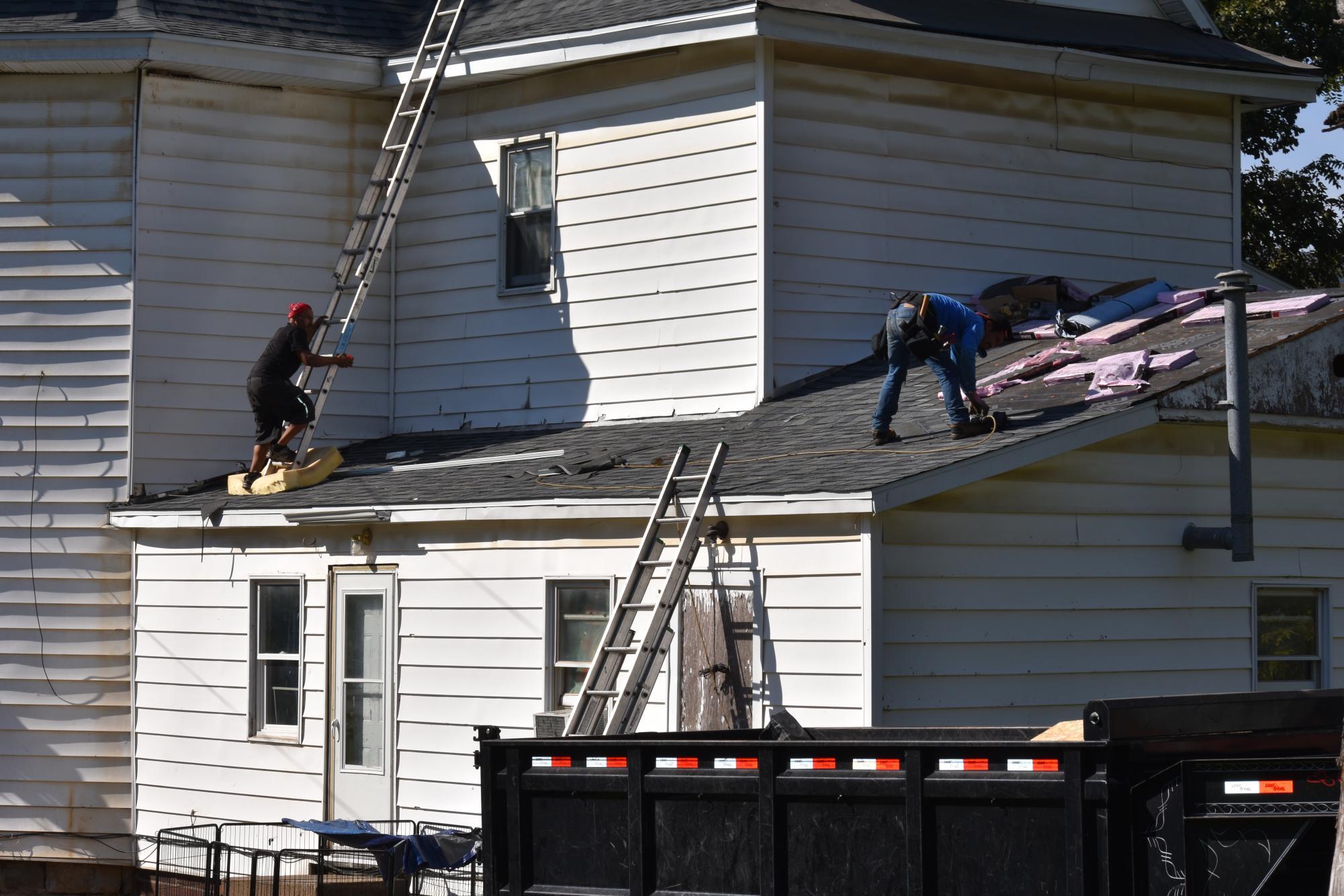 Workers repair roofs after a hailstorm in May 2023.