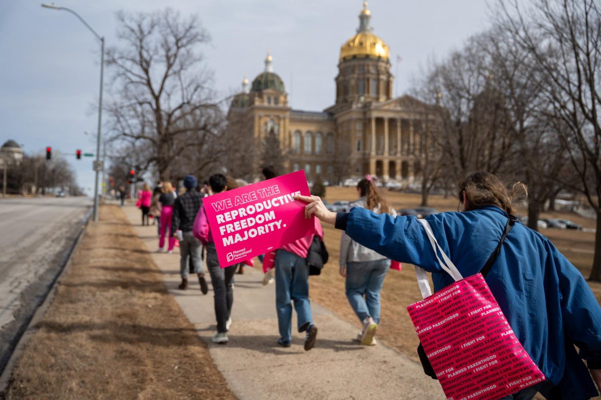 An event attendee holds out a sign on the walk to the Iowa Capitol during Lobby Day on Monday, Feb. 27, 2025.