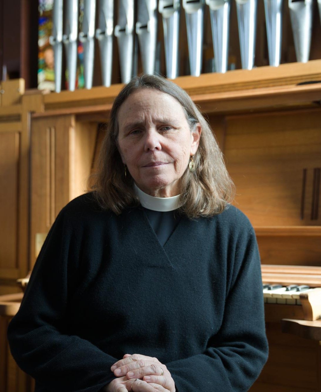 Rev. Wendy Abrahamson sits by the organ in St. Paul's Episcopal Church in Grinnell, Iowa.