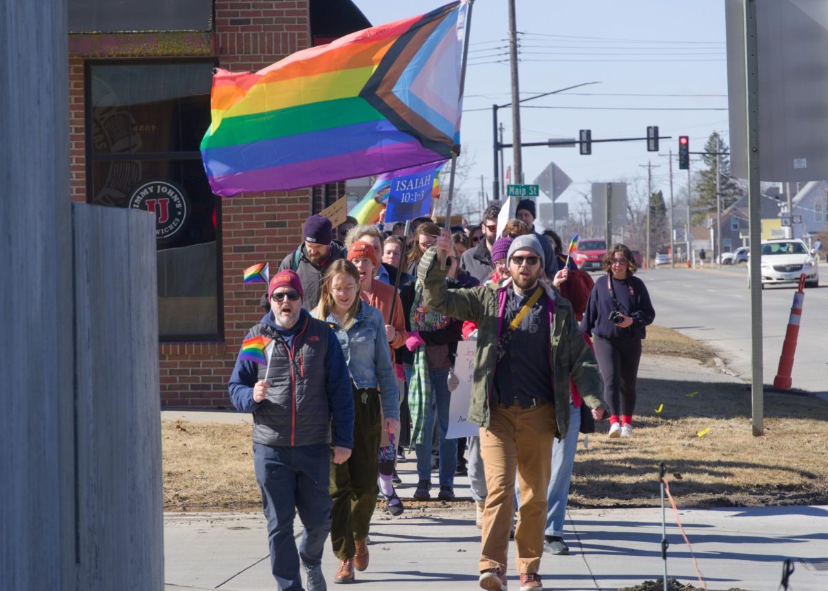 Protesters march down the streets of Grinnell, some holding Progress Pride Flags, on Thursday, Feb. 27. 