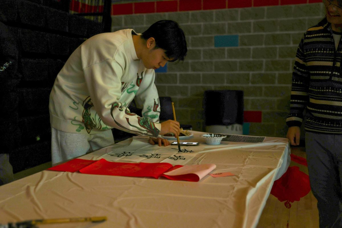 Zhengxi Li `26 carefully paints Chinese characters onto a thin sheet of paper.