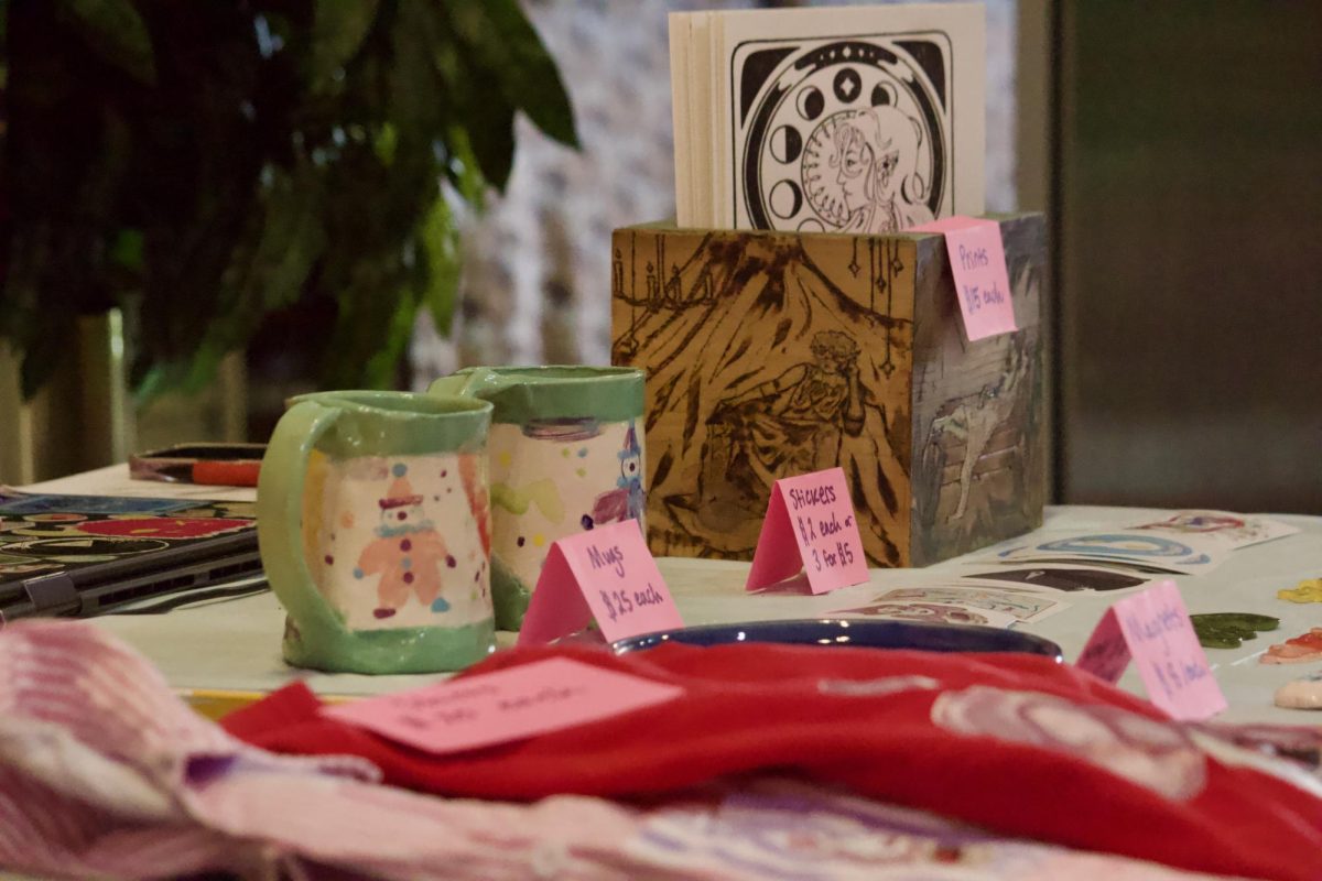 Products line a table displaying local artists' work for purchase at Saint's Rest Coffeehouse.