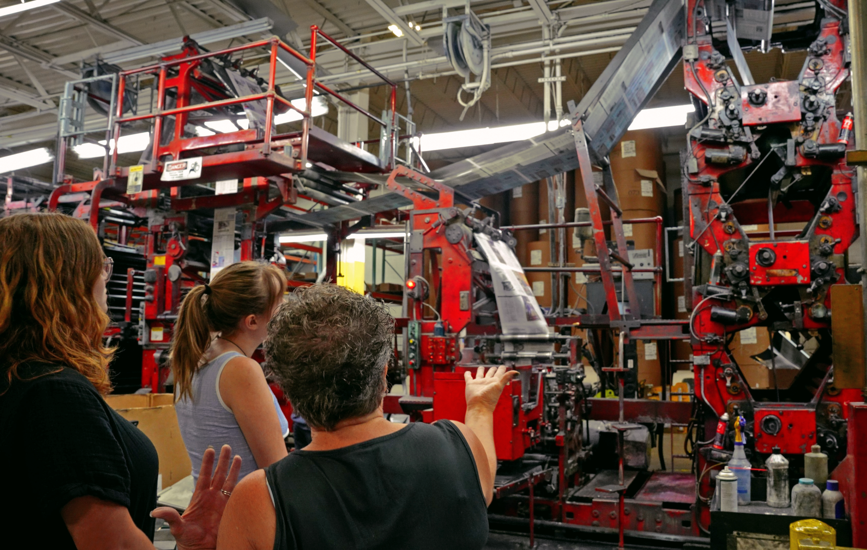 From left: S&B Features Editor Zoe Zappas `27 and Editor in Chief Taylor Nunley `26 walk through the printing process with Daily Freeman-Journal production and plant manager Angie Anderson as The S&B print paper flies across the machine.