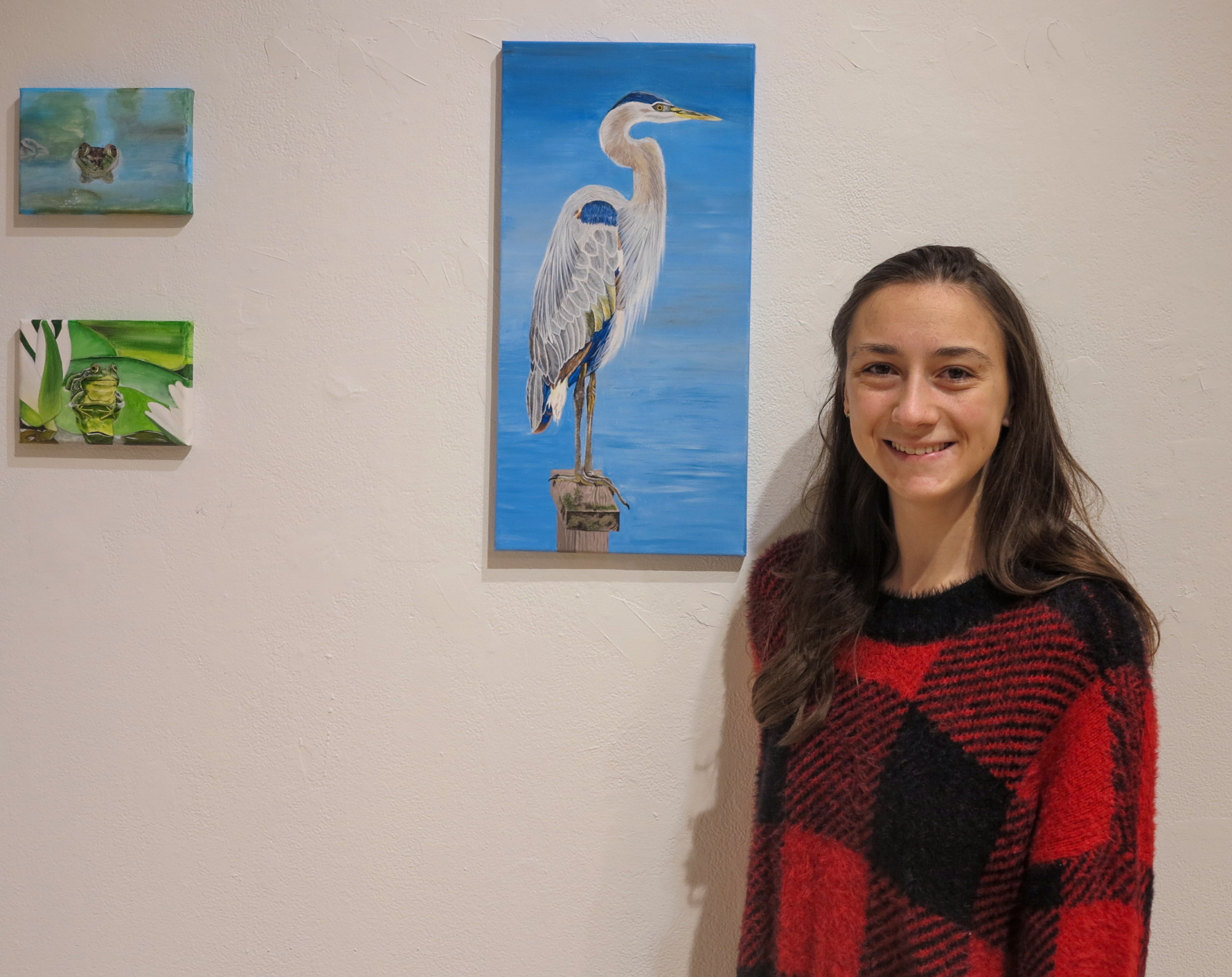 Courtney Cecil `26 stands next to a painting in her new Smith Gallery exhibit, “Welcome to the Woods.”