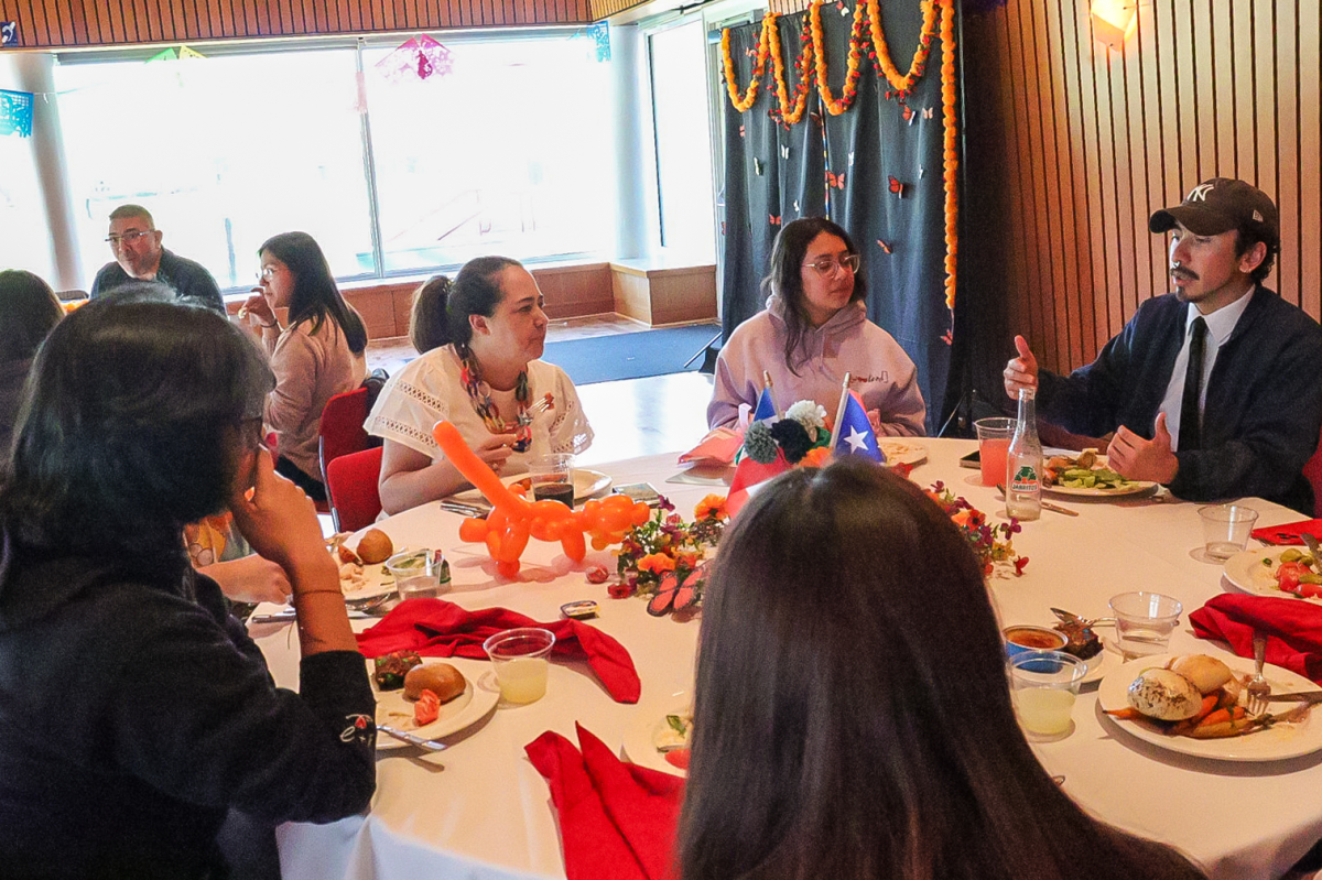 Amelia Lobo `99 (left) sits at table and talks to students about their time at Grinnell. 