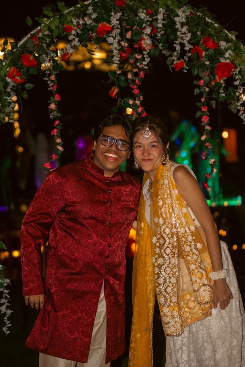 From left: Mock Shaadi groom and bride, Shibam Mukhopadhyay `26 and Jesi Rodriguez Beyer `26 pose for a photo under warm lighting and roses on the night of April 25, 2026.